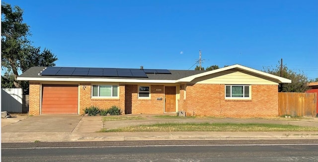 ranch-style house featuring a garage and solar panels