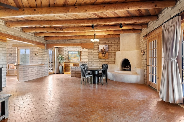 dining room with beamed ceiling, brick wall, an inviting chandelier, and wooden ceiling