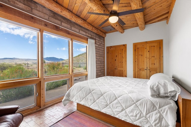 bedroom featuring beam ceiling, a mountain view, wood ceiling, and multiple windows