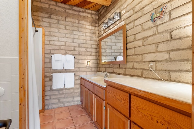 bathroom featuring vanity, tile patterned floors, and brick wall