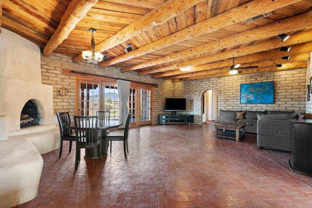 dining area featuring beamed ceiling, brick wall, a chandelier, and wood ceiling