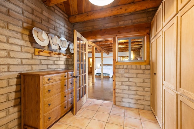 hall featuring light tile patterned flooring and brick wall