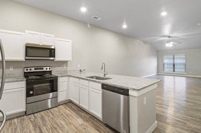 kitchen featuring a ceiling fan, a peninsula, a sink, appliances with stainless steel finishes, and white cabinetry