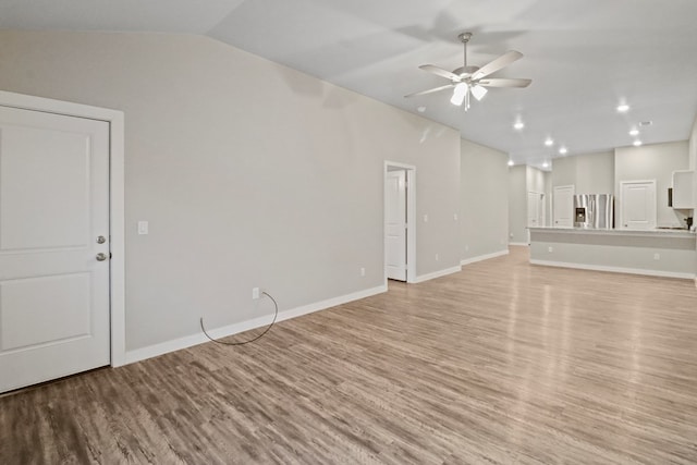 unfurnished living room with baseboards, light wood-style floors, ceiling fan, and vaulted ceiling