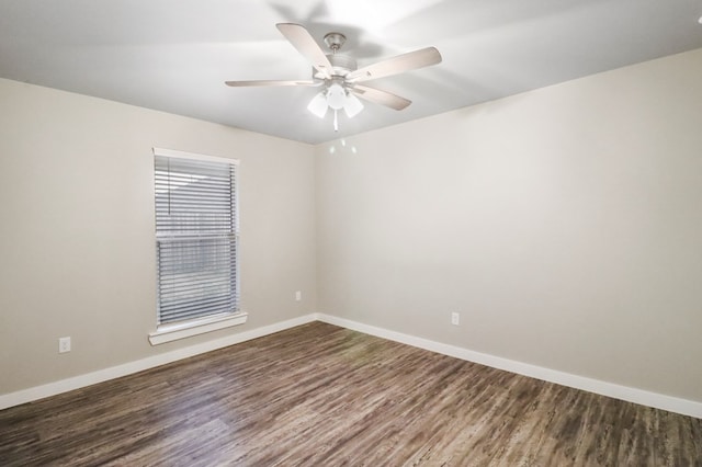 unfurnished room with dark wood-type flooring, a ceiling fan, and baseboards