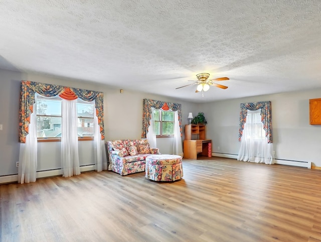 702/704 S Wilbur Ave, Sayre, PA 18840 - sitting room featuring a baseboard heating unit, light wood-style floors, a textured ceiling, and a ceiling fan