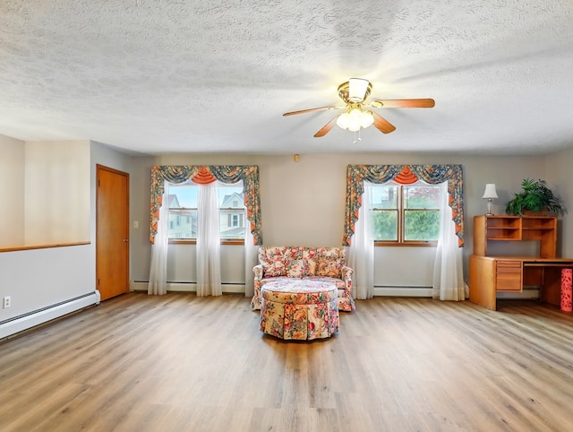 702/704 S Wilbur Ave, Sayre, PA 18840 - living area with healthy amount of natural light, a baseboard radiator, wood finished floors, a ceiling fan, and a textured ceiling