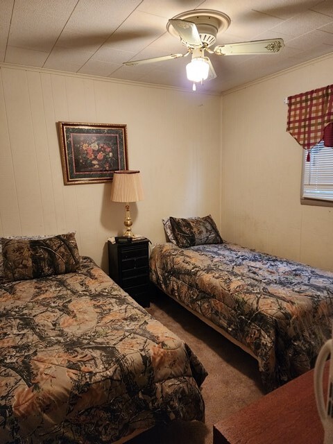 carpeted bedroom with a ceiling fan and ornamental molding