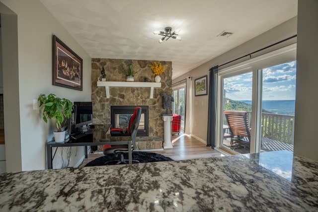 home office featuring a fireplace, a water view, and light hardwood / wood-style floors