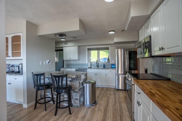 kitchen with white cabinets, stainless steel appliances, and butcher block counters