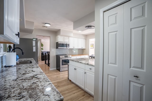 kitchen with sink, stainless steel appliances, light hardwood / wood-style flooring, backsplash, and white cabinets