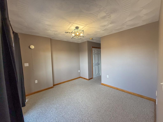 empty room featuring carpet and a notable chandelier