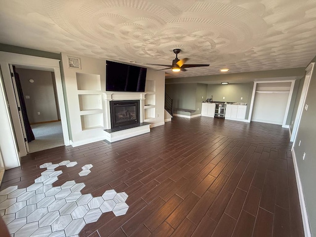 unfurnished living room with hardwood / wood-style floors, built in shelves, and ceiling fan