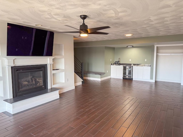 unfurnished living room featuring ceiling fan, built in features, beverage cooler, and dark hardwood / wood-style floors