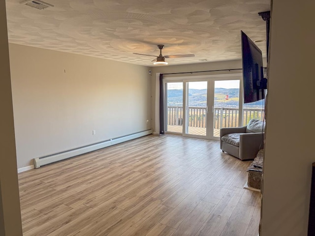 unfurnished room with a textured ceiling, light hardwood / wood-style floors, ceiling fan, and a baseboard heating unit