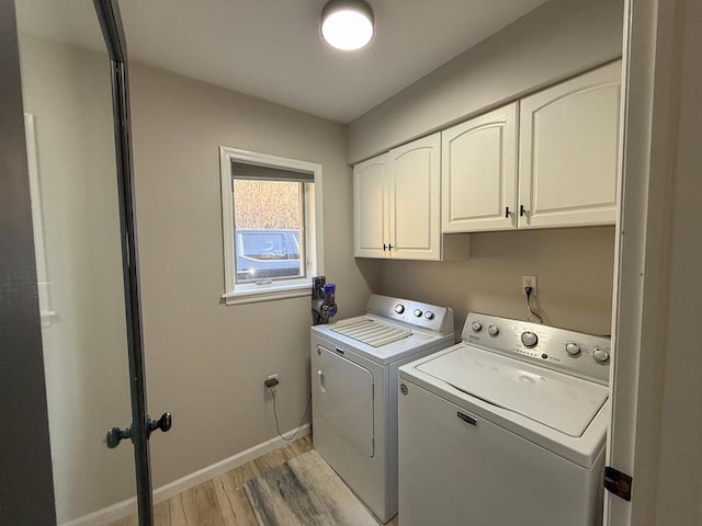 laundry room featuring cabinets, separate washer and dryer, and light hardwood / wood-style flooring