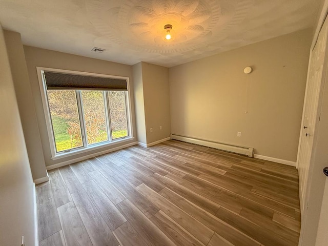 empty room featuring hardwood / wood-style flooring and baseboard heating