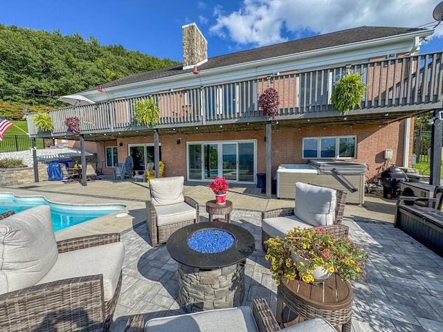 back of house featuring a balcony, a patio, a fire pit, and a pool with hot tub