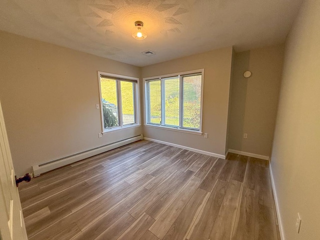 spare room with baseboard heating and wood-type flooring