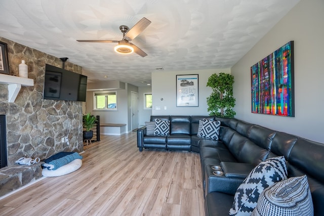 living room with ceiling fan, a textured ceiling, and hardwood / wood-style flooring