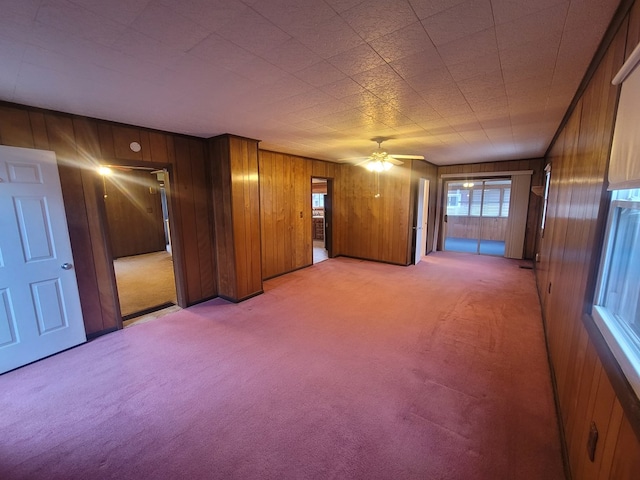 carpeted empty room featuring wood walls and ceiling fan