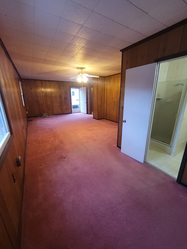 spare room featuring wooden walls, light carpet, and ceiling fan