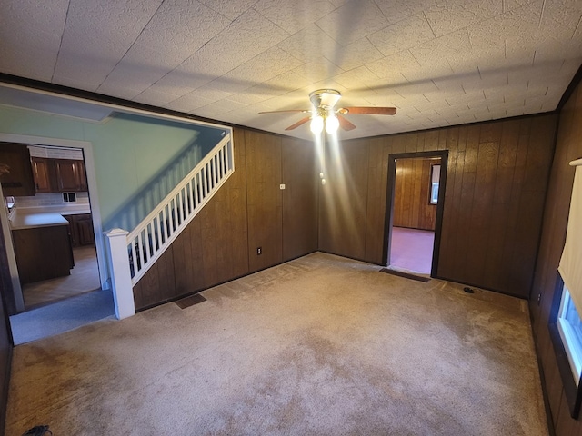 carpeted spare room featuring ceiling fan and wood walls