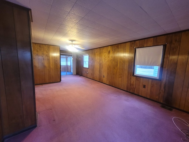 carpeted empty room with wood walls