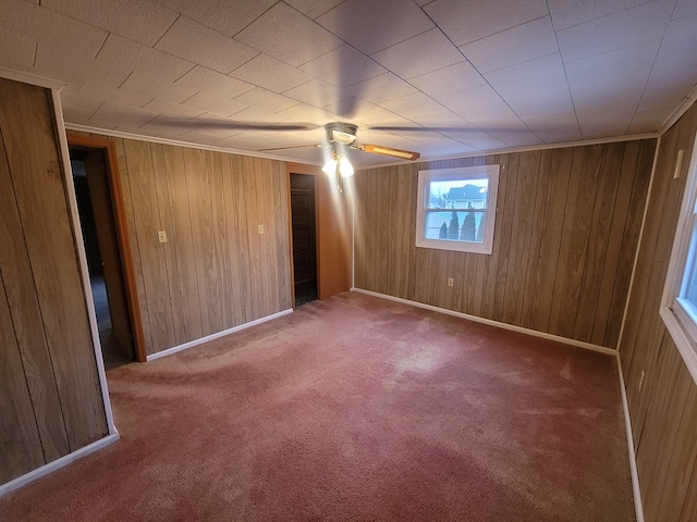 spare room featuring ceiling fan, carpet floors, and wood walls