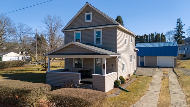 view of front of home with driveway, covered porch, an outdoor structure, a front lawn, and a garage