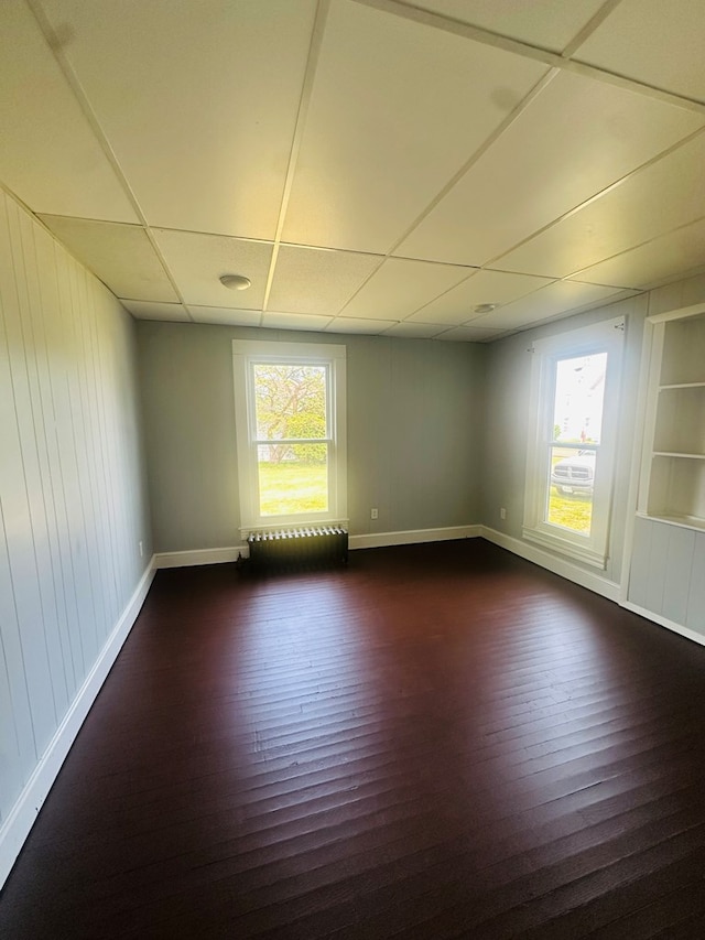 228 Willow St, Athens, PA 18810 - empty room featuring built in features, dark wood-style floors, a drop ceiling, baseboards, and wood walls