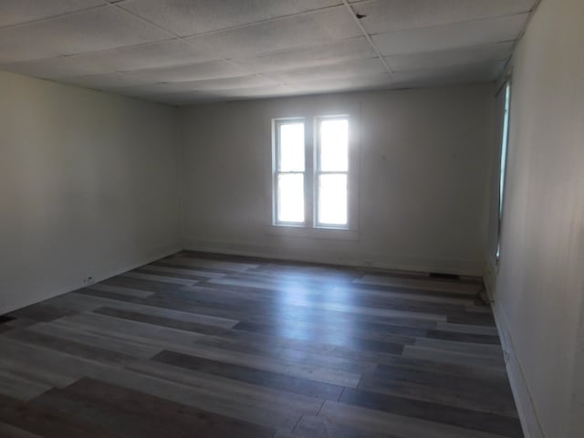 unfurnished room with a paneled ceiling and dark hardwood / wood-style floors