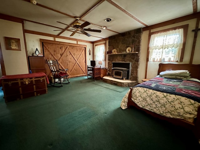 bedroom featuring carpet flooring, a wood stove, ceiling fan, and multiple windows