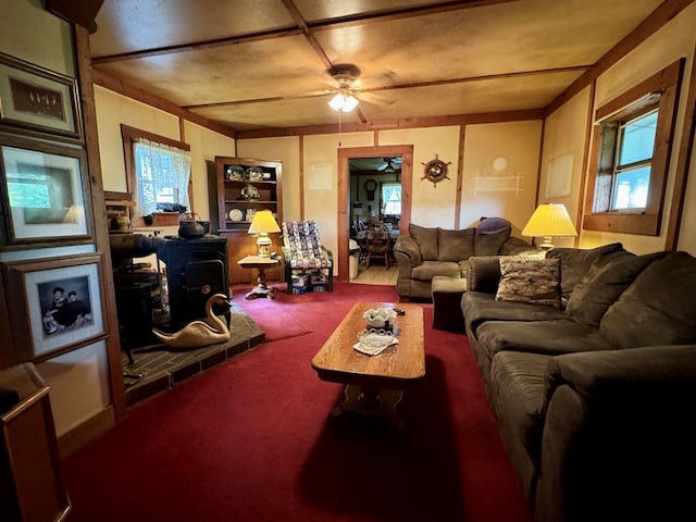 living room featuring carpet flooring, a wood stove, and ceiling fan