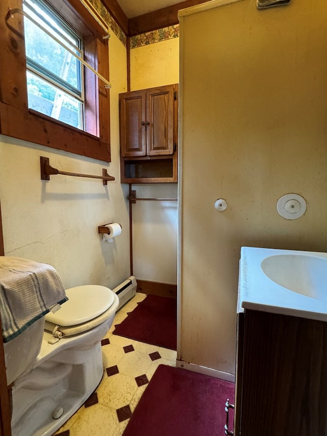 bathroom featuring toilet, vanity, and a baseboard heating unit