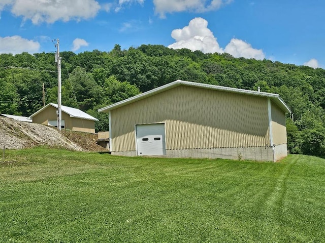40 W Hebron Rd, Coudersport, PA 16915 - view of property exterior featuring an outbuilding, a detached garage, a lawn, and a view of trees