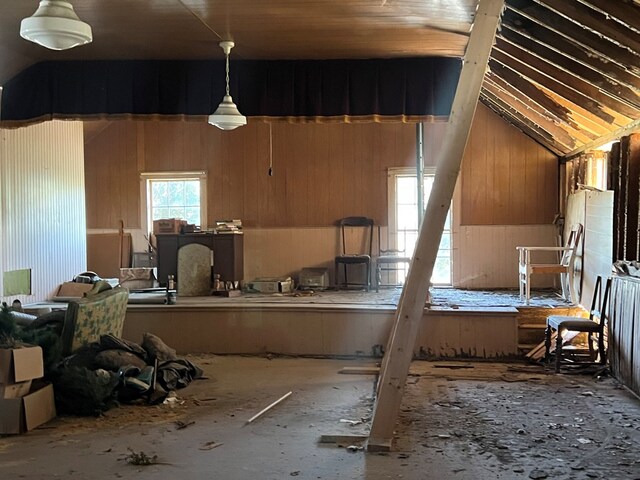 miscellaneous room featuring wood walls and vaulted ceiling