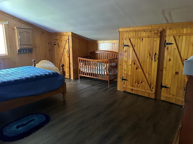 bedroom with vaulted ceiling, dark wood-type flooring, and wood walls