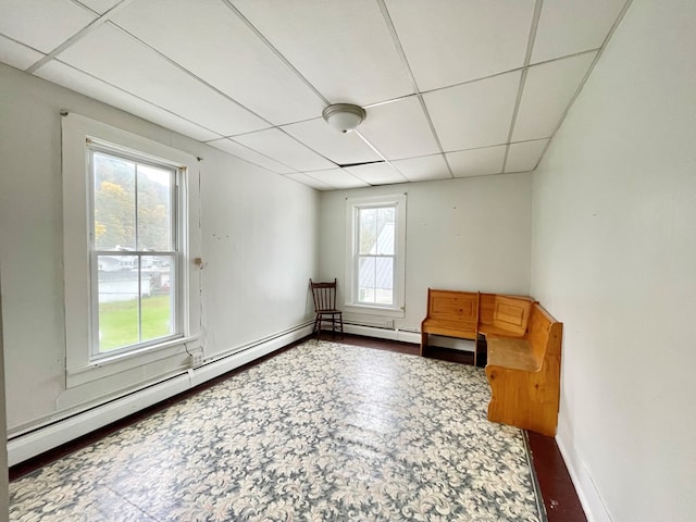 unfurnished room featuring a paneled ceiling and a baseboard heating unit