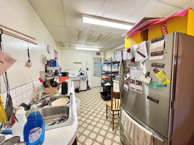 kitchen featuring a paneled ceiling, stainless steel fridge, and sink