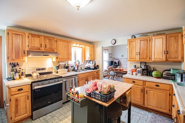 kitchen featuring stainless steel electric range, sink, tasteful backsplash, tile counters, and dishwashing machine