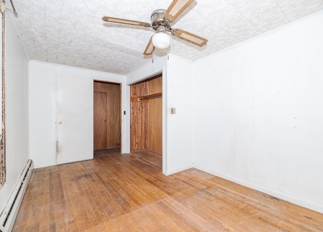 empty room featuring ceiling fan, crown molding, wood-type flooring, and baseboard heating