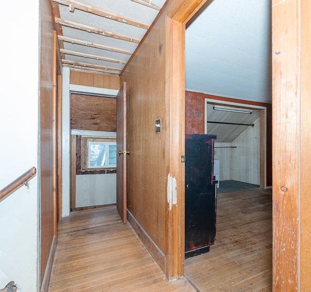 hall featuring light hardwood / wood-style flooring and wooden walls