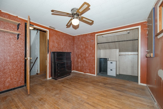 unfurnished bedroom with ceiling fan, wood-type flooring, and crown molding