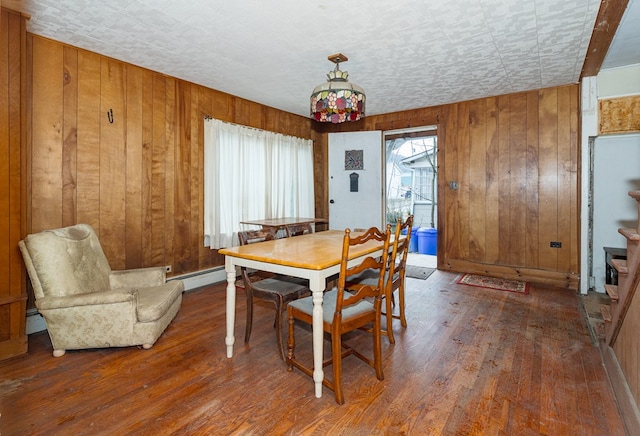 dining area with wooden walls, a baseboard radiator, and wood-type flooring