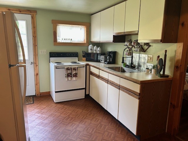 kitchen featuring white cabinetry, white appliances, sink, and parquet floors