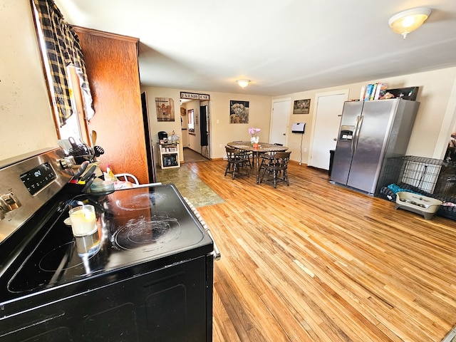 kitchen featuring light wood finished floors, electric range, and stainless steel refrigerator with ice dispenser