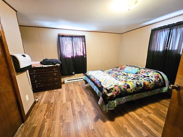 bedroom with baseboard heating and light wood finished floors