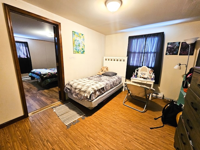 bedroom with radiator heating unit, baseboards, and wood finished floors