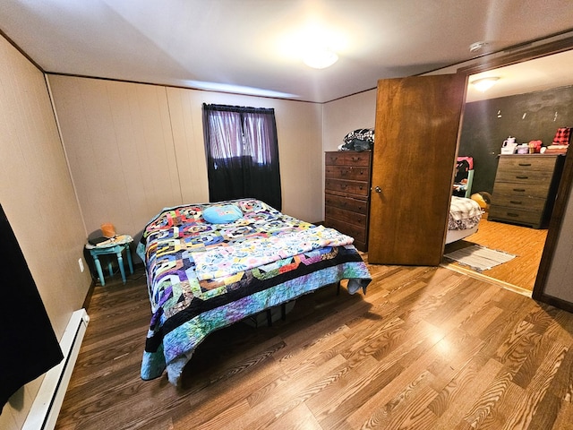 bedroom featuring baseboard heating and wood finished floors